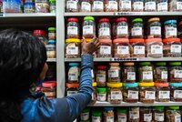 Woman pulling seed containers off the shelf.