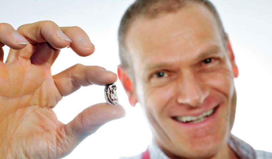 Dr. Debouck holding up a bean.