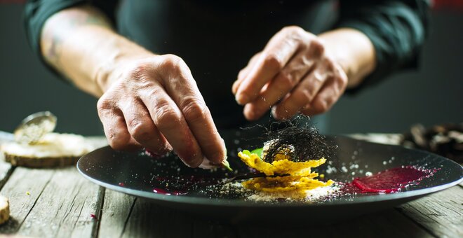 Close-up of male hands cooking molecular dish. Dark background. Molecular cuisine