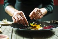 Close-up of male hands cooking molecular dish. Dark background. Molecular cuisine