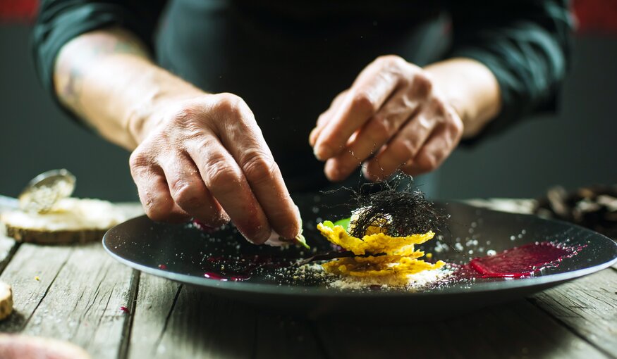 Close-up of male hands cooking molecular dish. Dark background. Molecular cuisine