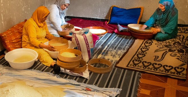 Women sitting with baskets of rice.