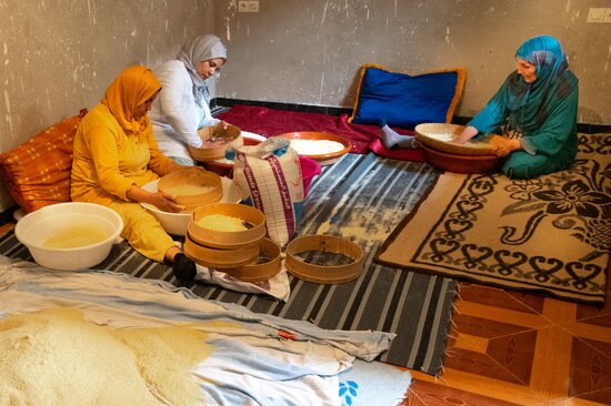 Women sitting with baskets of rice. 