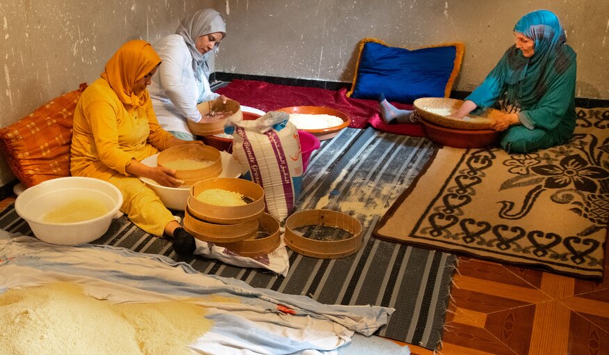 Women sitting with baskets of rice.