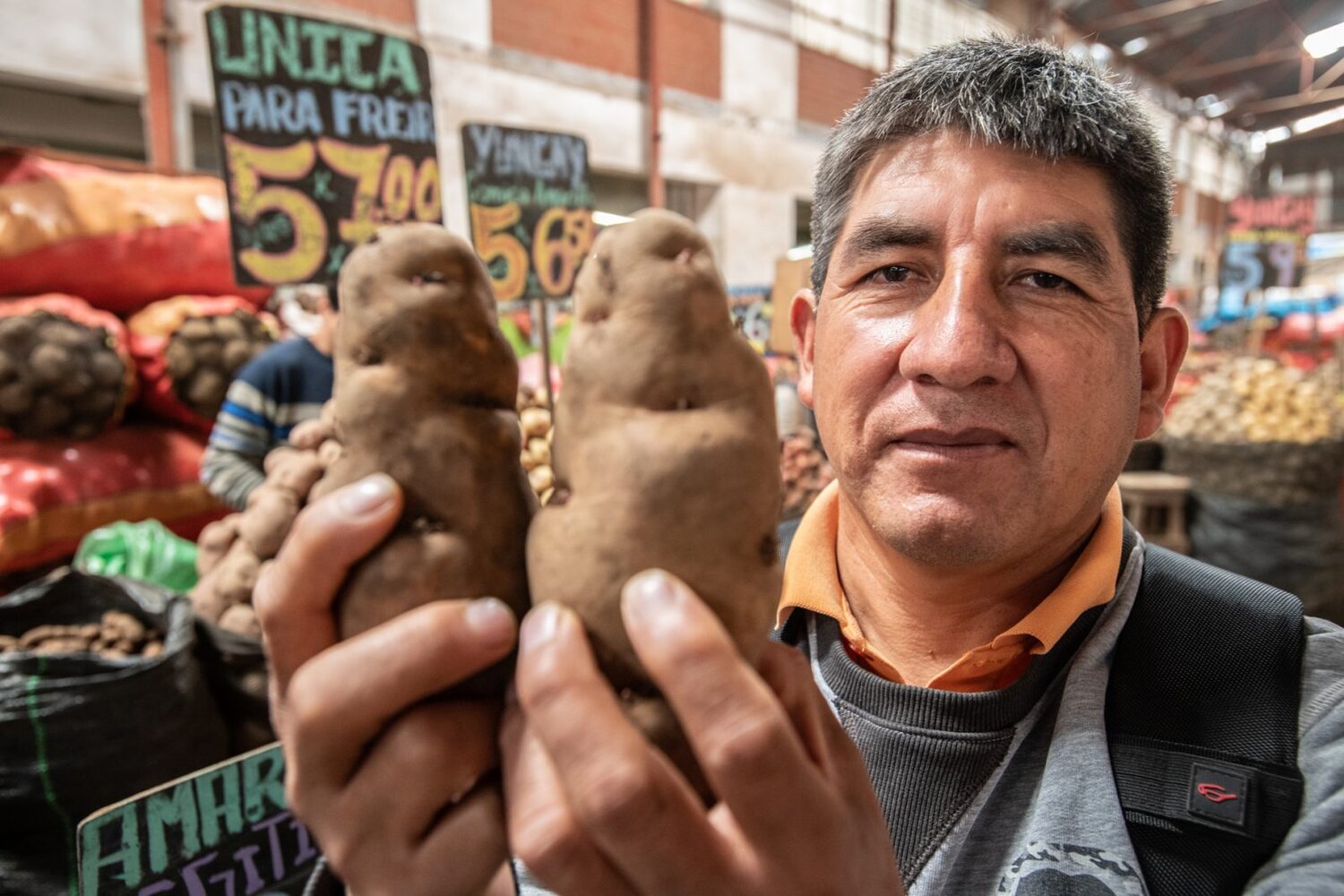 Man holding potatoes at a market.