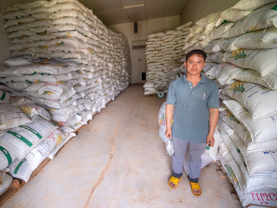 Man standing in front of bags of seeds. 