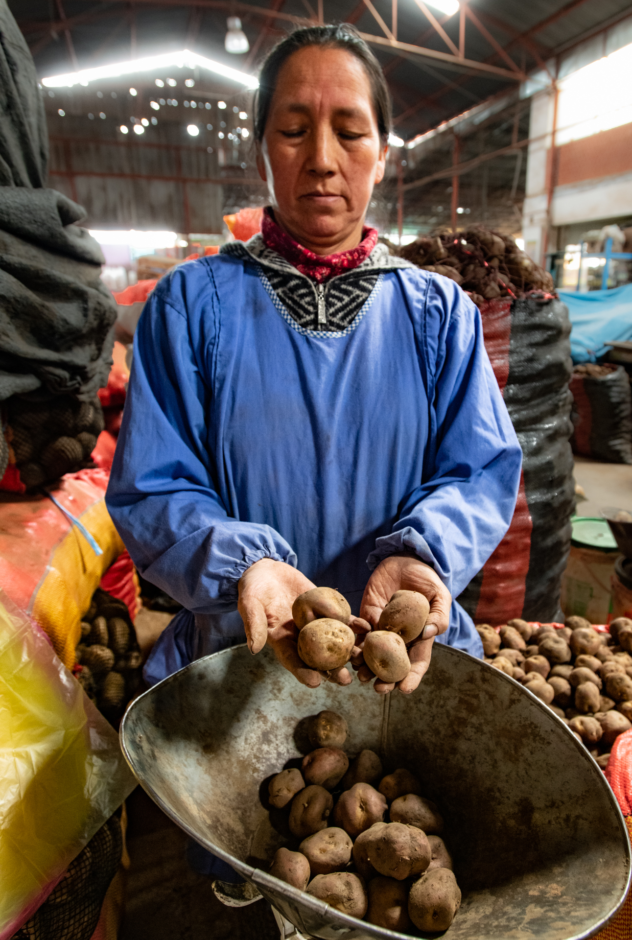 Woman selling potatoes at a market.