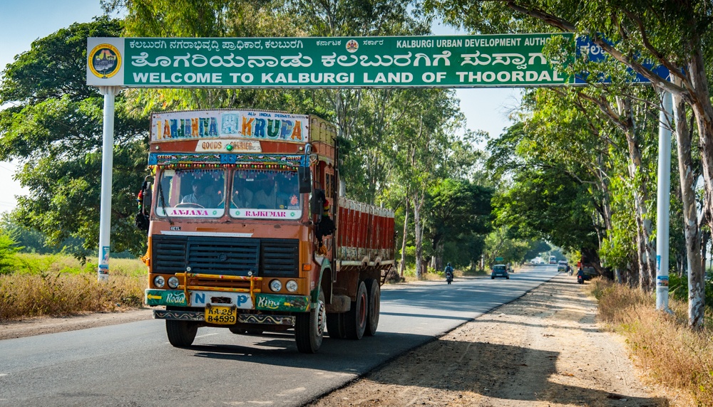 Truck driving on a street under welcome sign.