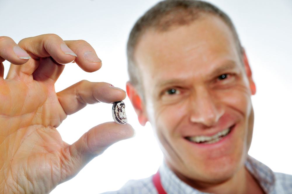 Dr. Debouck holding up a bean. 