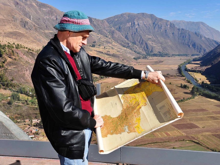 Dr. Debouck looking at a map in front of a mountain range. 