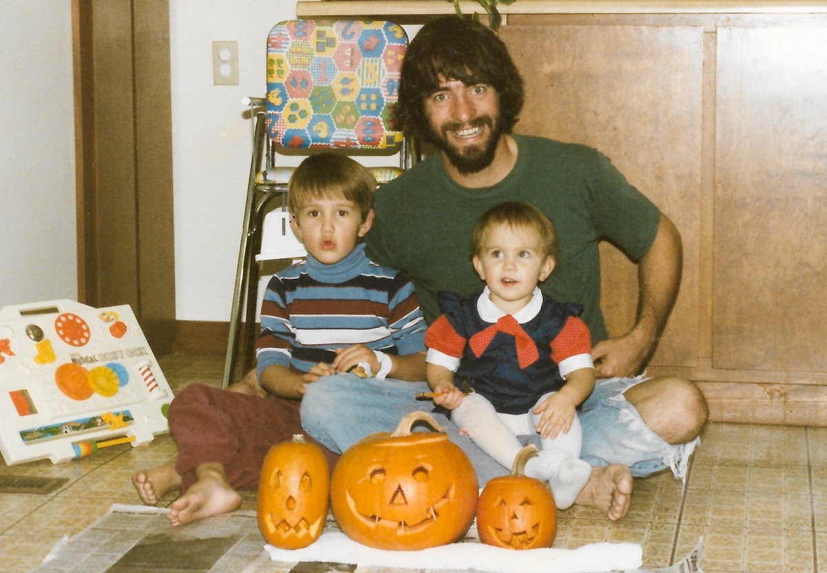 Dr. Ellis with his two children posing with carved pumpkins. 