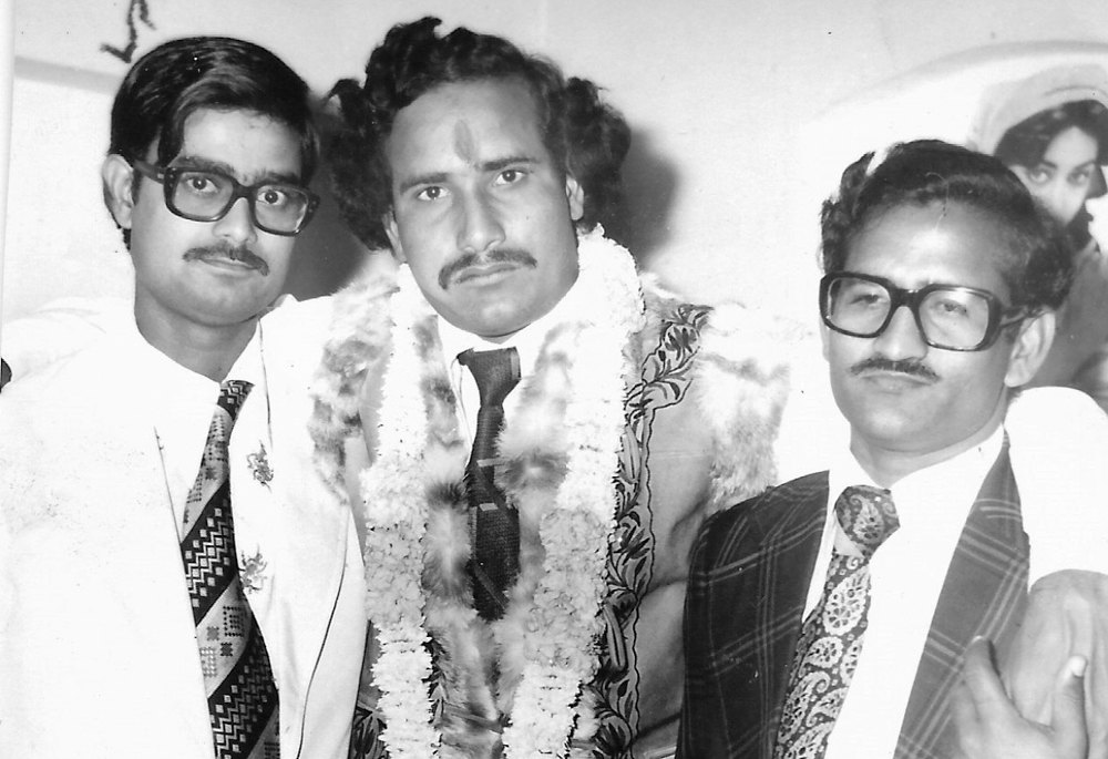 Dr. Upadhyaya standing with two men at engagement celebration. 
